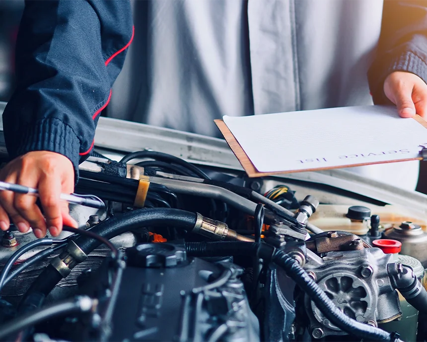 Mechaniker prüft den Motorraum eines Autos mit Servicecheckliste