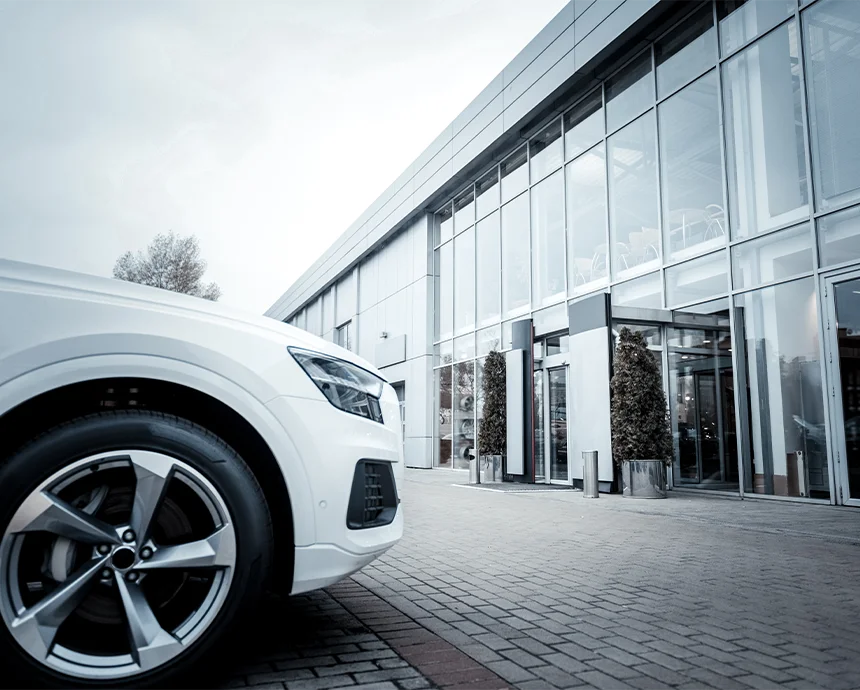 Weißes Auto vor einem modernen Autohausgebäude