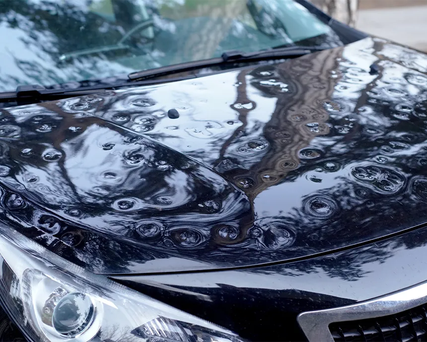 Sichtbare Hagelschäden auf der Motorhaube eines Fahrzeugs